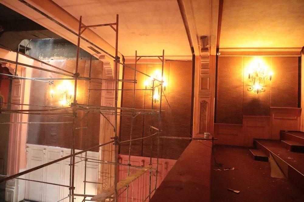 Scaffolding inside Le Colisée's hall below the balcony, lit by wall lamps